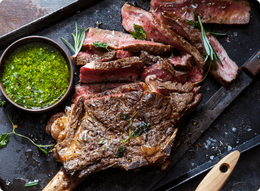 Juicy sliced steak on a cutting board with chimichurri sauce